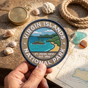 May include: Embroidered patch featuring a scenic view of the Virgin Islands National Park. The patch has a circular design with text that reads "Virgin Islands National Park, St. John, USVI, Est. 1956." The image depicts a beach, island, and ocean.