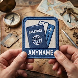 Op de afbeelding: Een blauwe geborduurde patch met een paspoort en instapkaart ontwerp. Het paspoort heeft het woord "PASSPORT" en een wereldbol afbeelding. De patch bevat ook het woord "ANYNAME". De patch wordt voor een vintage kaart gehouden.