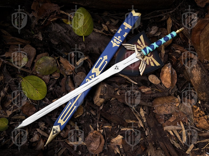 Pode incluir: Uma espada de fantasia com uma l&acirc;mina branca e detalhes dourados, repousando sobre uma cama de folhas e madeira. A espada tem uma empunhadura azul e dourada, com uma bainha a condizer e um escudo com um emblema dourado.