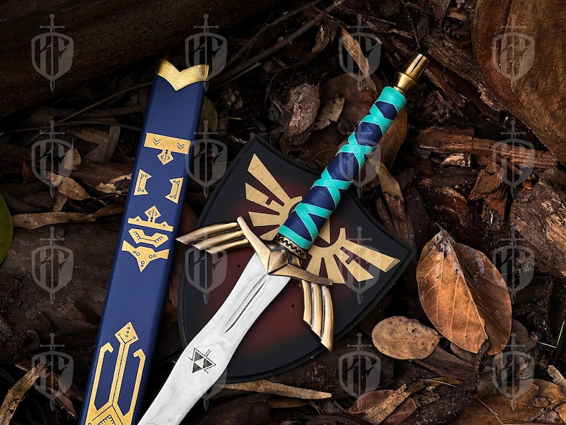 Pode incluir: Espada, escudo e bainha de fantasia. A espada tem uma l&acirc;mina prateada, uma guarda dourada e uma empunhadura enrolada em azul turquesa e marinho. O escudo &eacute; preto com um emblema dourado. A bainha &eacute; azul com detalhes dourados.