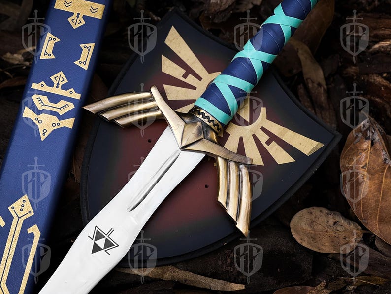 Pode incluir: Uma espada decorativa com uma l&acirc;mina branca e detalhes dourados, com uma empunhadura enrolada em azul e verde-azulado. Uma bainha azul combinando com desenhos dourados e um escudo preto com um emblema dourado tamb&eacute;m s&atilde;o vis&iacute;veis.