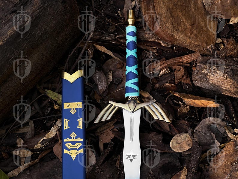 Pode incluir: Uma espada de fantasia com uma l&acirc;mina prateada e detalhes dourados. O punho &eacute; envolto em azul e turquesa, e a bainha &eacute; azul com detalhes dourados. A espada repousa sobre uma cama de folhas e madeira.