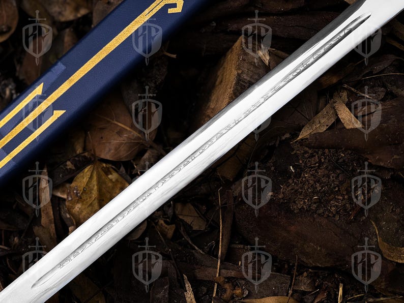 Pode incluir: Um close-up de uma l&acirc;mina de espada com desenhos gravados. A l&acirc;mina de a&ccedil;o polido est&aacute; em &acirc;ngulo, revelando detalhes da grava&ccedil;&atilde;o. Uma bainha azul com detalhes dourados &eacute; vis&iacute;vel no fundo, sugerindo um tema hist&oacute;rico ou de fantasia.