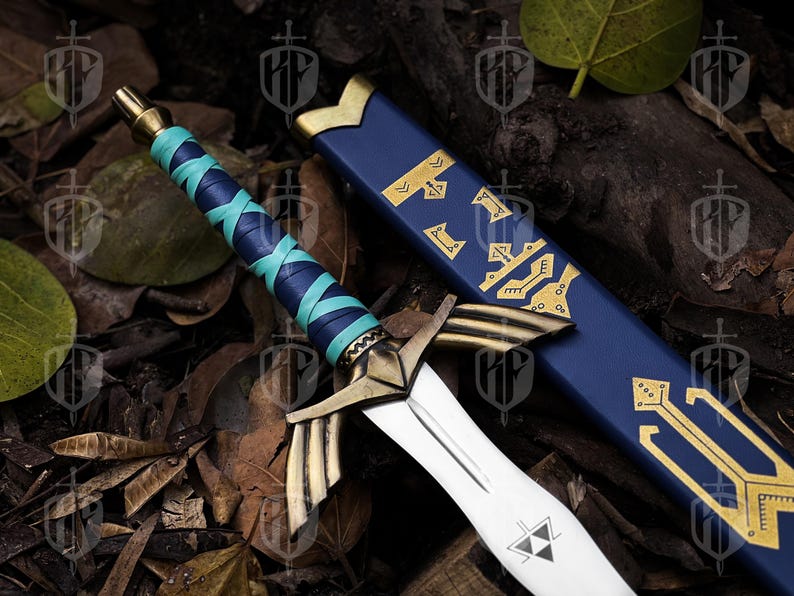 Pode incluir: Espada de fantasia com l&acirc;mina branca e detalhes dourados. O punho &eacute; envolto em couro azul e turquesa. A bainha azul apresenta padr&otilde;es dourados. A espada est&aacute; sobre um leito de folhas e galhos.