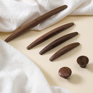 Może przedstawiać: Zestaw trzech ceramicznych kubków z nakrapianym, matowym wykończeniem. Kubki są w odcieniach kremu, jasnego brązu i ciemnego brązu. Każdy kubek ma prosty, minimalistyczny design.