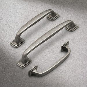 May include: Three antique-style cabinet pulls in a weathered silver finish. Each pull features a curved handle and square mounting plates. The hardware is arranged on a grey surface, showcasing the design and texture of the metal.