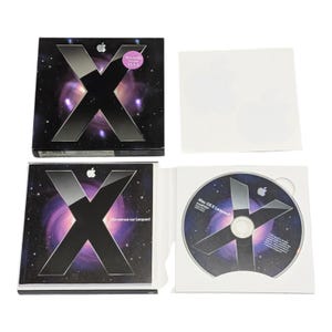 May include: A Mac OS X Leopard software package including a square box with a large black X and galaxy background, a manual with the text Bienvenue sur Leopard, and an installation DVD featuring the same X design and Apple logo on a disc.