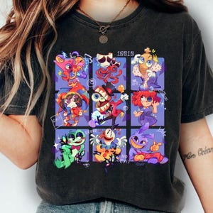 Op de afbeelding: Donkergrijs T-shirt met een kleurrijke cartoonafbeelding. De afbeelding is een raster van negen unieke karakters met verschillende ontwerpen en de woorden "ERROR", "EXIT" en "NO EXIT". Het shirt is gemaakt van een zacht materiaal.