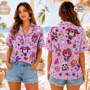 Pode incluir: Uma camisa de manga curta com botões em tom lilás claro, apresentando um padrão repetitivo de personagens de desenhos animados, máscaras e corações. A camisa inclui um pequeno emblema no peito com o nome Sophia bordado em letras cursivas.