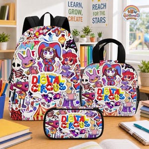 Op de afbeelding: Een rugzak, een lunchtas en een etui met een kleurrijke collage van personages en de tekst The Amazing Digital Circus. Elk item heeft zwarte banden of randen en toont een levendig patroon van stripfiguren, waaronder een nar.