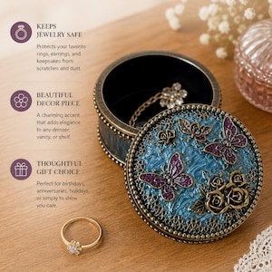 Può includere: Un portagioie decorativo con un design blu e oro, con farfalle e rose. La scatola è aperta, rivelando un anello. Il testo sull'immagine recita "A Treasure for Every Moment."