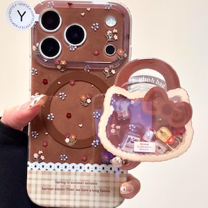 May include: A brown phone case with a clear back, decorated with small flowers and a lace trim. A matching purse-shaped phone grip is attached. The case has the text "Spring to summer autumn harvest winter Tibet we have a long future."