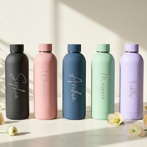 Puede incluir: Cinco botellas de agua personalizadas en negro, rosa, azul, verde y morado. Cada botella tiene un nombre en cursiva: Sophia, Winnie, Archie, Maggie y Yelly. Las botellas son cilíndricas con tapón de rosca y tienen una capacidad de 500 ml.