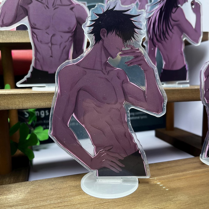 May include: Transparent acrylic standee featuring a shirtless anime character with black hair and black shorts. The standee is on a white base and is displayed on a wooden shelf. Other similar standees are visible in the background.