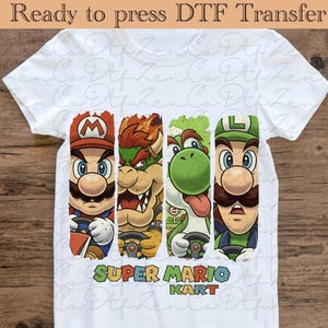May include: White t-shirt featuring a colorful graphic of Mario, Bowser, Yoshi, and Luigi from Super Mario Kart, each holding a steering wheel. The text "SUPER MARIO KART" is below the characters. The shirt also has the text "Ready to press DTF Transfer".