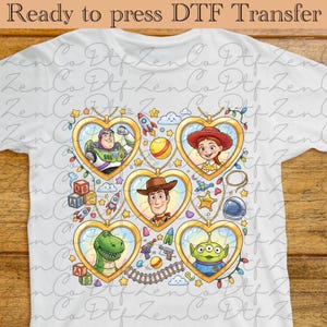 Peut inclure: T-shirt blanc avec un motif de transfert DTF représentant des personnages de Toy Story. Le motif comprend Buzz l'Éclair, Jessie, Woody, Rex et un extraterrestre, chacun dans un cadre en forme de cœur. Le texte "Ready to press DTF Transfer" est en haut.