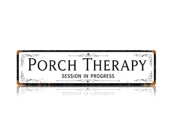 Può includere: Una targa rettangolare in metallo bianco con un bordo usurato color ruggine. Il testo recita "PORCH THERAPY" in un grande carattere serif nero, seguito da "SESSION IN PROGRESS" in un carattere sans-serif nero più piccolo, incorniciato da volute nere.