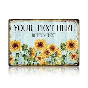 May include: Rectangular metal sign with a light blue background and a sunflower design. The sign has the text "YOUR TEXT HERE" and "BOTTOM TEXT" in black. The sunflowers are yellow and brown.