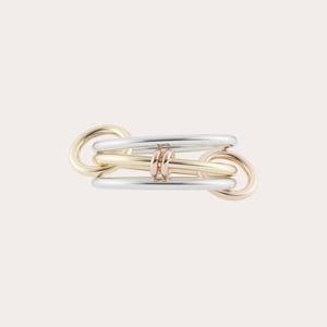 Op de afbeelding: Een ring met meerdere tinten met een geschakeld ontwerp. De ring bevat goud, zilver en roségouden elementen, met in elkaar grijpende cirkelvormen. Het ontwerp is modern en minimalistisch, geschikt voor dagelijks gebruik.