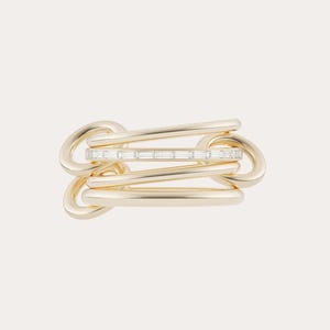 Op de afbeelding: Een goudkleurige ring met een uniek geschakeld ontwerp. De ring heeft een centrale band versierd met kleine, rechthoekig geslepen edelstenen. Het ontwerp is modern en elegant, geschikt voor dagelijks gebruik of speciale gelegenheden.