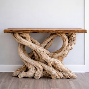 Puede incluir: Una consola rústica con una tapa de madera natural y una base hecha de madera flotante entrelazada de color claro. La tapa es de un marrón cálido, contrastando con los tonos más claros de la base. Esta pieza única añade un toque de decoración inspirada en la naturaleza.