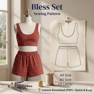 May include: A red and brown plaid pajama set, consisting of a crop top and shorts, displayed on a mannequin. A sewing pattern illustration of the set is pinned to the wall. The text "Bless Set Sewing Pattern" is at the top. Additional sewing notions are visible.