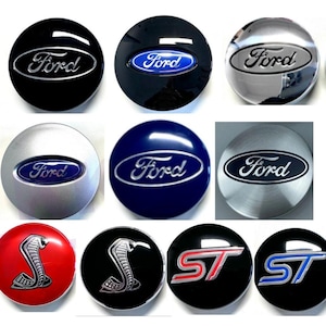 Puede incluir: Una colección de tapacubos de coche Ford en varios colores, incluyendo negro, plateado y azul. Algunas tapas presentan el logotipo de Ford, mientras que otras muestran los emblemas Cobra o ST. Las tapas son redondas y tienen un acabado brillante.