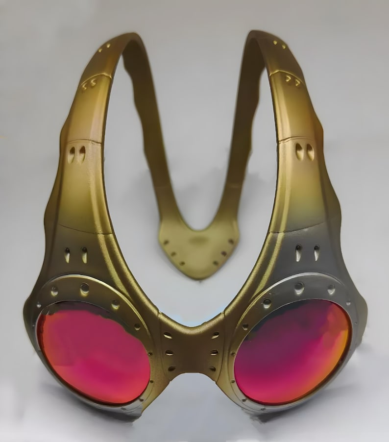 Authentische goldene Oakley Over-The-Top (OTT) Sonnenbrille auf weißem Grund. Das seltene Archive-Piece besticht durch einen matten Goldrahmen in skulpturalem Over-the-head Design. Die kreisrunden Spiegelgläser zeigen einen Verlauf von leuchtendem Gelbgold zu Orange. Mit industriellen Belüftungsschlitzen und Nieten-Details ist dieses Sammlerstück ein Highlight für Techwear-, Gorpcore- und Avantgarde-Enthusiasten sowie Oakley-Liebhaber.
