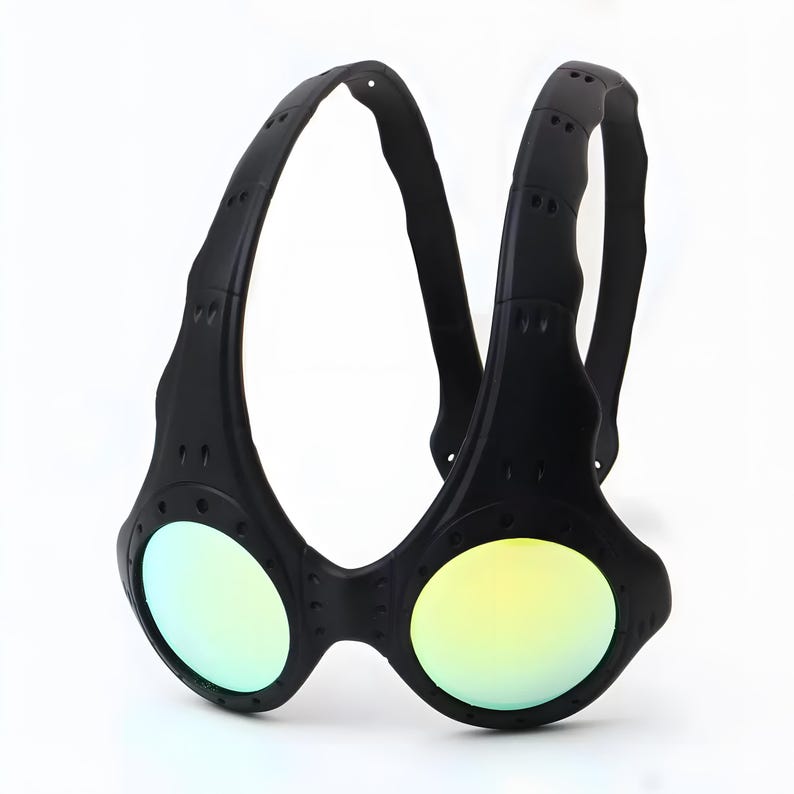 Authentic black Oakley Over-The-Top (OTT) sunglasses on a white background. This rare archive piece features a matte black sculptural frame with a unique over-the-head dual-arch design. The circular mirrored lenses show a vibrant gradient from gold to coral-orange. Detailed with industrial vents and rivets, this high-fashion collectible represents a pinnacle of Oakley’s futuristic bio-design, perfect for techwear, gorpcore, and avant-garde enthusiasts.