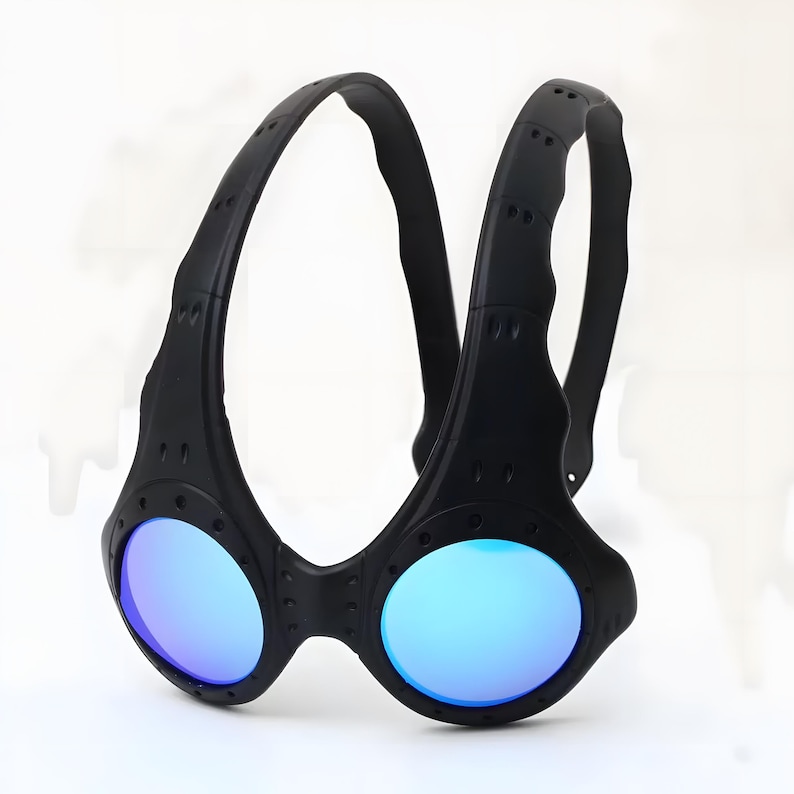 Authentic black Oakley Over-The-Top (OTT) sunglasses on a white background. This rare archive piece features a matte black sculptural frame with a unique over-the-head dual-arch design. The circular mirrored lenses show a vibrant gradient from gold to coral-orange. Detailed with industrial vents and rivets, this high-fashion collectible represents a pinnacle of Oakley’s futuristic bio-design, perfect for techwear, gorpcore, and avant-garde enthusiasts.