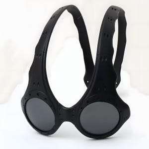 Authentic black Oakley Over-The-Top (OTT) sunglasses on a white background. This rare archive piece features a matte black sculptural frame with a unique over-the-head dual-arch design. The circular mirrored lenses show a vibrant gradient from gold to coral-orange. Detailed with industrial vents and rivets, this high-fashion collectible represents a pinnacle of Oakley’s futuristic bio-design, perfect for techwear, gorpcore, and avant-garde enthusiasts.