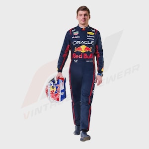 Może przedstawiać: Ciemnogranatowy kombinezon wyścigowy z logo Oracle Red Bull Racing, oznaczeniami sponsorów i czerwonymi paskami po bokach. Kombinezon jest noszony z pasującym biało-niebiesko-czerwonym kaskiem wyścigowym trzymanym w jednej dłoni.