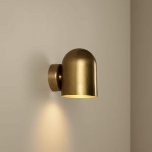 May include: A white ceramic mug with a black handle and the text "But First, Coffee" in a bold, black font. The mug is set against a blurred background, suggesting a cozy setting.