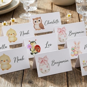 Può includere: Una collezione di segnaposto bianchi con illustrazioni ad acquerello di animali e motivi pasquali. Ogni biglietto presenta un nome in elegante calligrafia, perfetto per una festa primaverile o pasquale. I biglietti sono disposti su un tavolo di legno rustico.