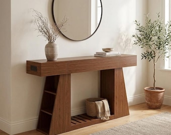 May include: A brown wooden console table featuring a long top surface, a side section with three open shelves, and a bottom slatted shelf. The table includes a built-in power outlet on the side and a drawer, providing storage and display space.