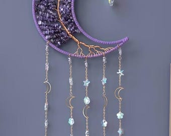 May include: A celestial-themed wall hanging featuring a crescent moon shape in purple, filled with amethyst stones. Gold-colored wire forms a tree design. Dangling from the moon are chains with crystals, moons, stars, and blue agate slices. A decorative piece.