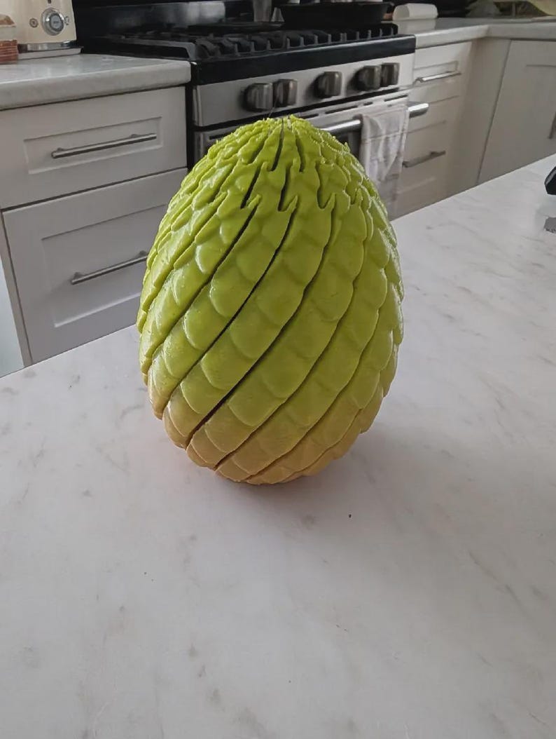 Pu&ograve; includere: Un oggetto a forma di uovo color verde lime con una superficie ruvida simile a delle scaglie. La struttura presenta distinti strati o segmenti orizzontali che avvolgono l'intera forma, creando un aspetto stratificato dalla cima alla base.