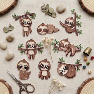 May include: A collection of eight embroidered sloth patches in various poses, including hanging from branches, lying down, and standing. The sloths are brown with cream-colored faces and large black eyes, featuring green leaf accents on the branches.