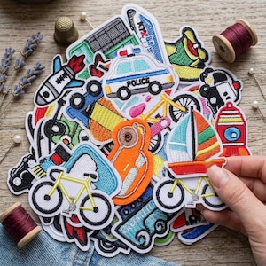Puede incluir: Una colección de parches de tela bordados de colores con varios diseños, incluyendo un coche de policía con el texto POLICE, una bicicleta amarilla, un velero, cohetes y otros vehículos, dispuestos en un montón con artículos de costura.