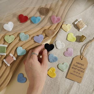 May include: A set of 20 small embroidered heart patches in various colors including red, blue, pink, white, yellow, and black. The set includes spools of thread, a thimble, and a brown paper tag labeled HANDMADE Embroidered HEART PATCHES - SET OF 20 - CURATED COLLECTION.