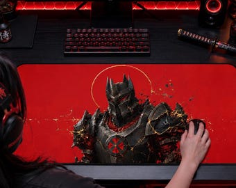 May include: A rectangular desk mat featuring a central graphic of a dark, armored warrior with glowing red eyes and gold accents set against a solid red background. The mat is positioned on a black desk surface in front of a computer monitor.