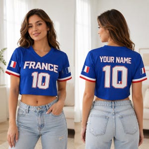 以下が含まれることがあります： 「FRANCE」の文字と数字の「10」が白でプリントされた青色のクロップトップジャージ。袖には赤と白のトリム、フランス国旗のグラフィックが入っています。ジャージの背面には「YOUR NAME」と数字の「10」と書かれています。