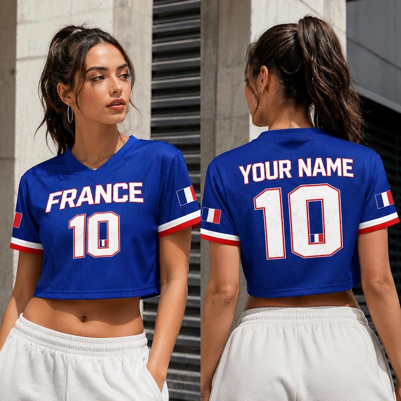 以下が含まれることがあります： 白文字で「FRANCE」と数字の「10」がプリントされた青色のクロップトップジャージ。袖には赤と白のトリムと小さなフランス国旗が付いています。ジャージの背面には「YOUR NAME」と数字の「10」がプリントされています。