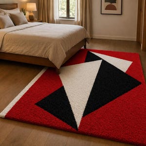May include: A geometric area rug with a red background and black and white triangular shapes. The rug is placed in a bedroom with a wooden bed frame and a nightstand.