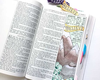 May include: A Bible page with a hand-drawn illustration of mountains and waves. The text on the page reads "Whosoever shall say unto this mountain, Be thou removed, and be thou cast into the sea; and shall not doubt in his heart, but shall believe that those things which he saith shall come to pass; he shall have whatsoever he saith."