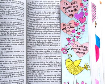 May include: A colorful bookmark with the text "He will rejoice over thee with joy," "He will rest in his love," and "He will joy over thee with singing." The bookmark features hearts, musical notes, and a yellow bird illustration. The text "Zephaniah 3:17" is also included.