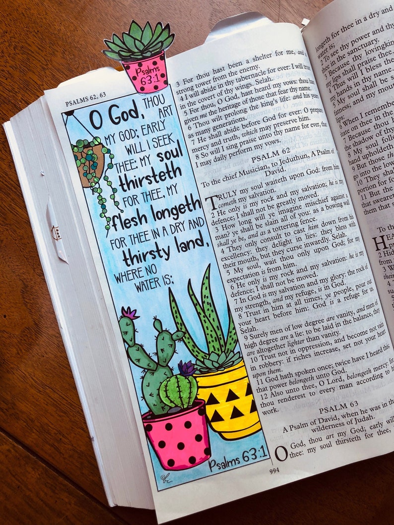 May include: A page from a Bible with a hand-drawn illustration of three potted succulents. The text on the page reads "O God, thou art my God; early will I seek thee: my soul thirsteth for thee, my flesh longeth for thee in a dry and thirsty land, where no water is." The illustration is in a watercolour style with pink, yellow, and green colours.