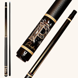 May include: A black pool cue featuring a textured leather wrap, gold accents, and a prominent letter P graphic with a crown motif. The word Parker is written in script below the letter. The cue includes a Uni-Loc joint and a black shaft with a blue tip.