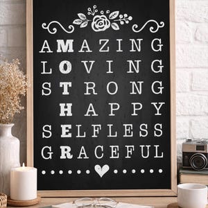 Puede incluir: Pizarra negra enmarcada con letras blancas. Se muestran las palabras "AMAZING, LOVING, STRONG, HAPPY, SELFLESS, GRACEFUL". Un diseño floral está en la parte superior y un corazón en la inferior. El marco es marrón.