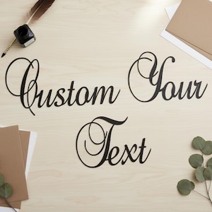 May include: Black cursive text spelling "Custom Your Text" on a light wood surface. The image includes a quill pen, inkwell, envelopes, and greenery, suggesting stationery or personalised items.